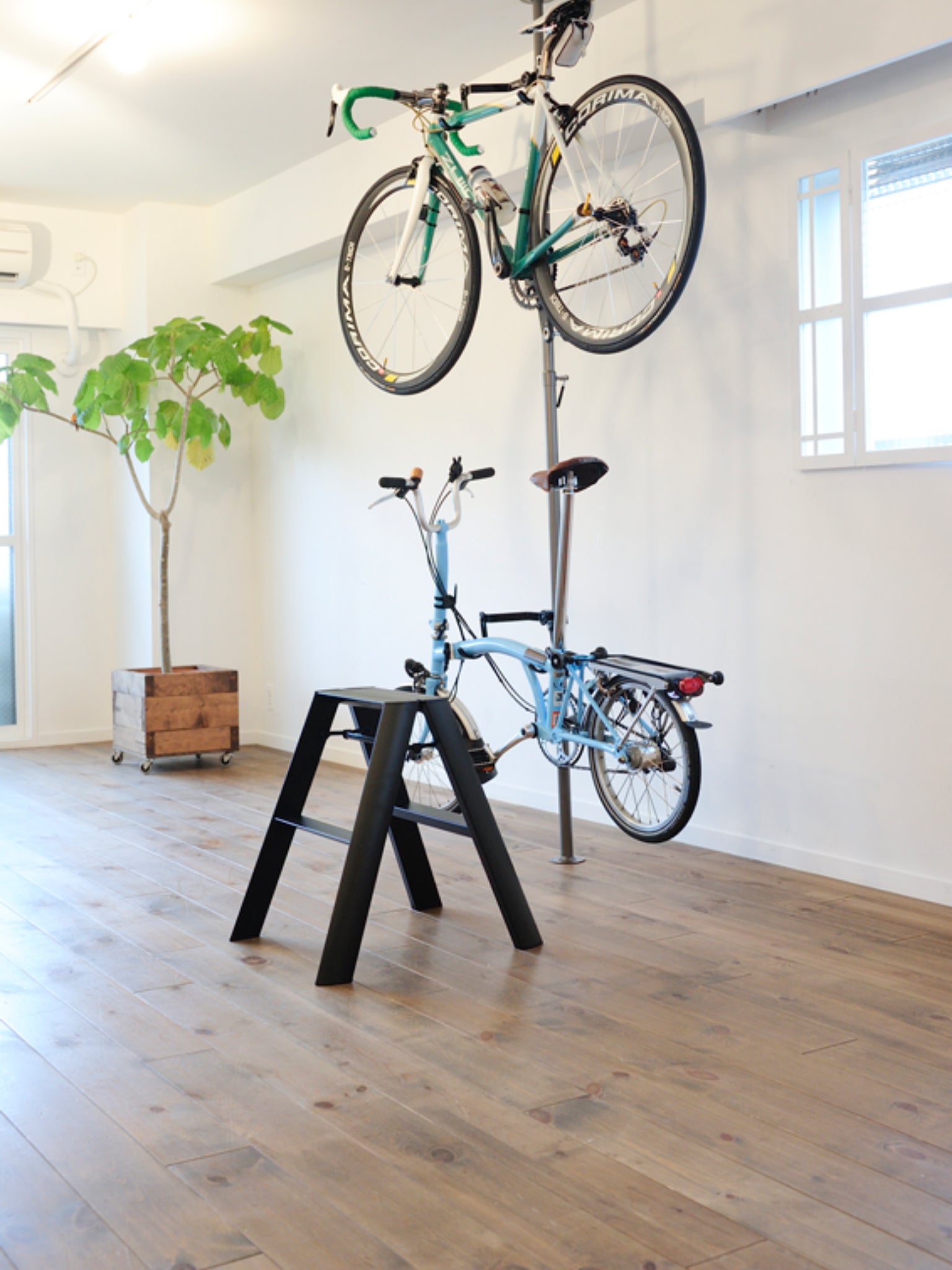 Zwarte designladder naast tafel als hulp in de garage met fietsen